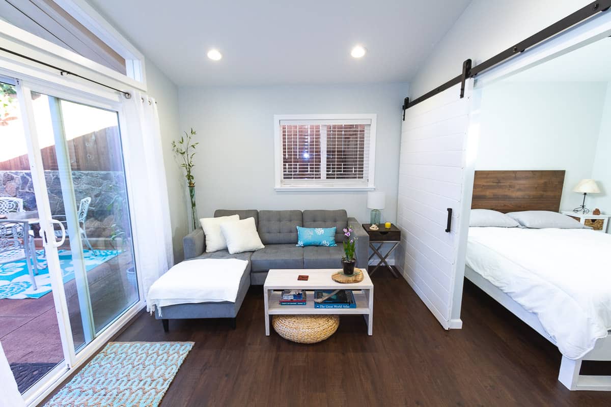 Living room with sliding glass door, gray couch and white barn door