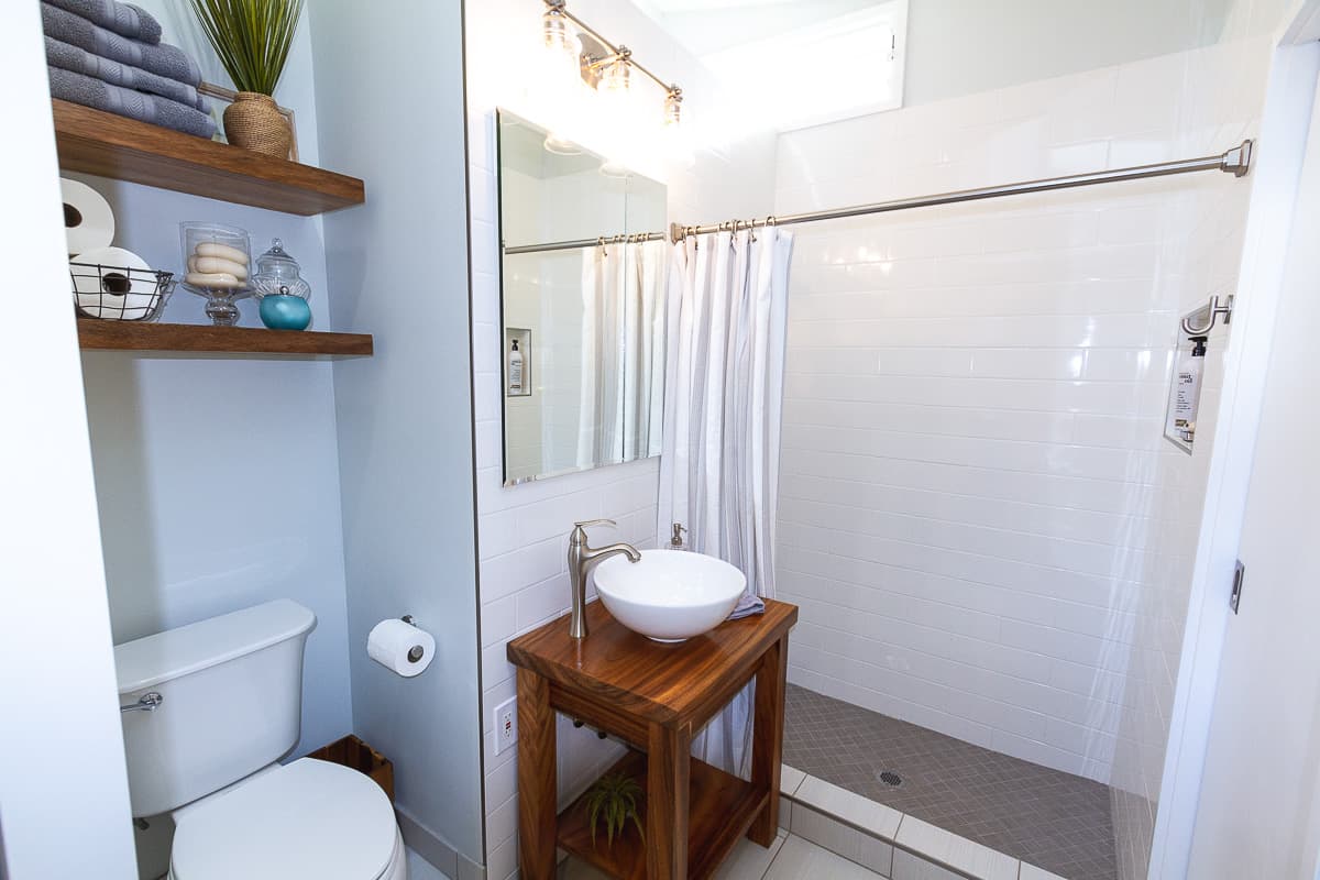 bathroom with white tiled shower and wood vanity
