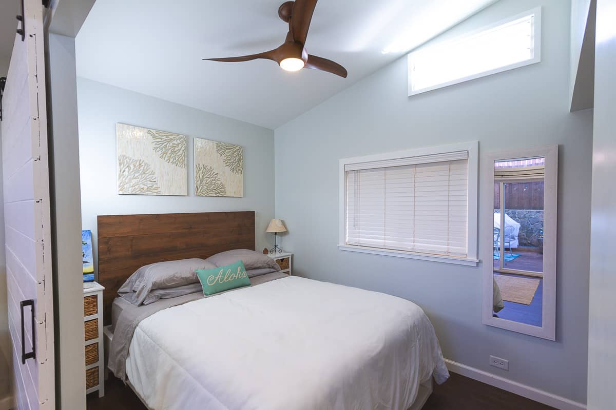 Bedroom with queen bed, mirror on the wall and ceiling fan