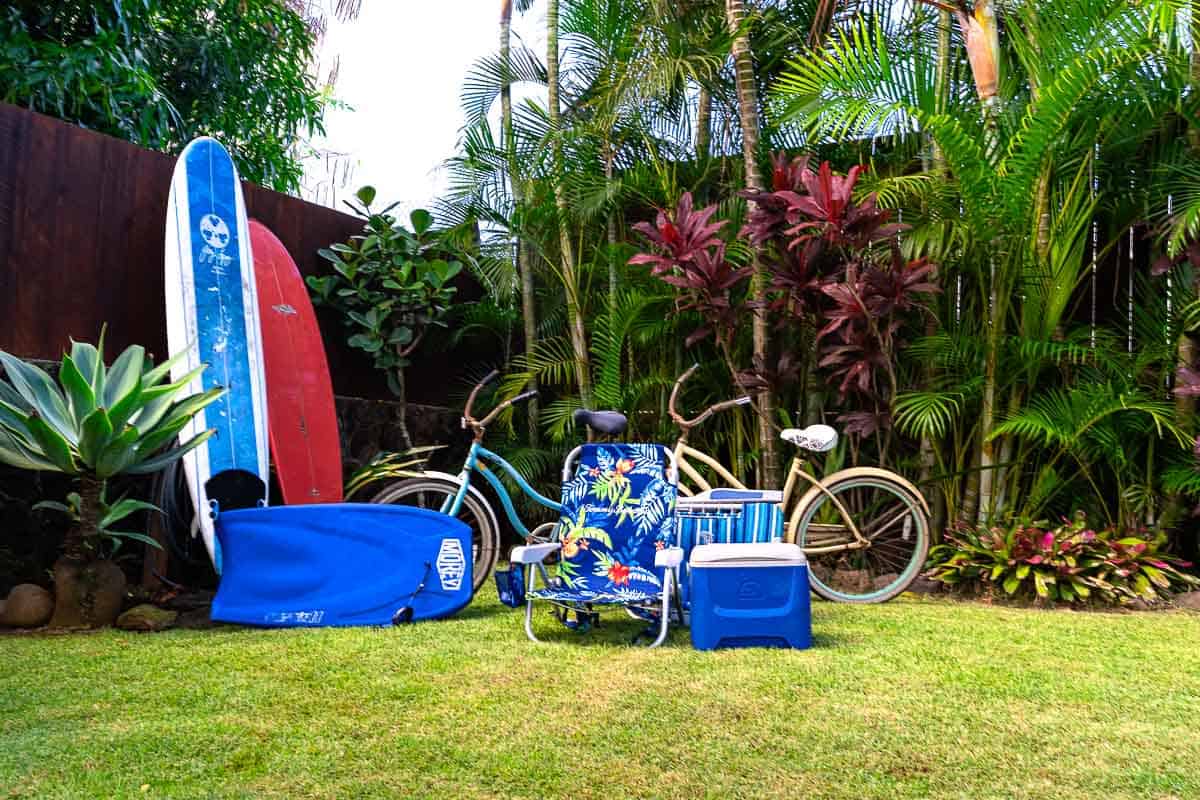 Beach gear for guests, including surfboards, chairs, cooler, and bikes.